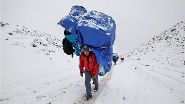 Портер идет с массивной нагрузкой к базовому лагерю Эверест