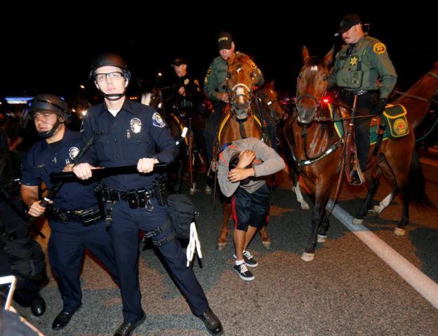 Полиция держит назад оппонентов козыря в Costa Mesa, Калифорния, 28-ое апреля